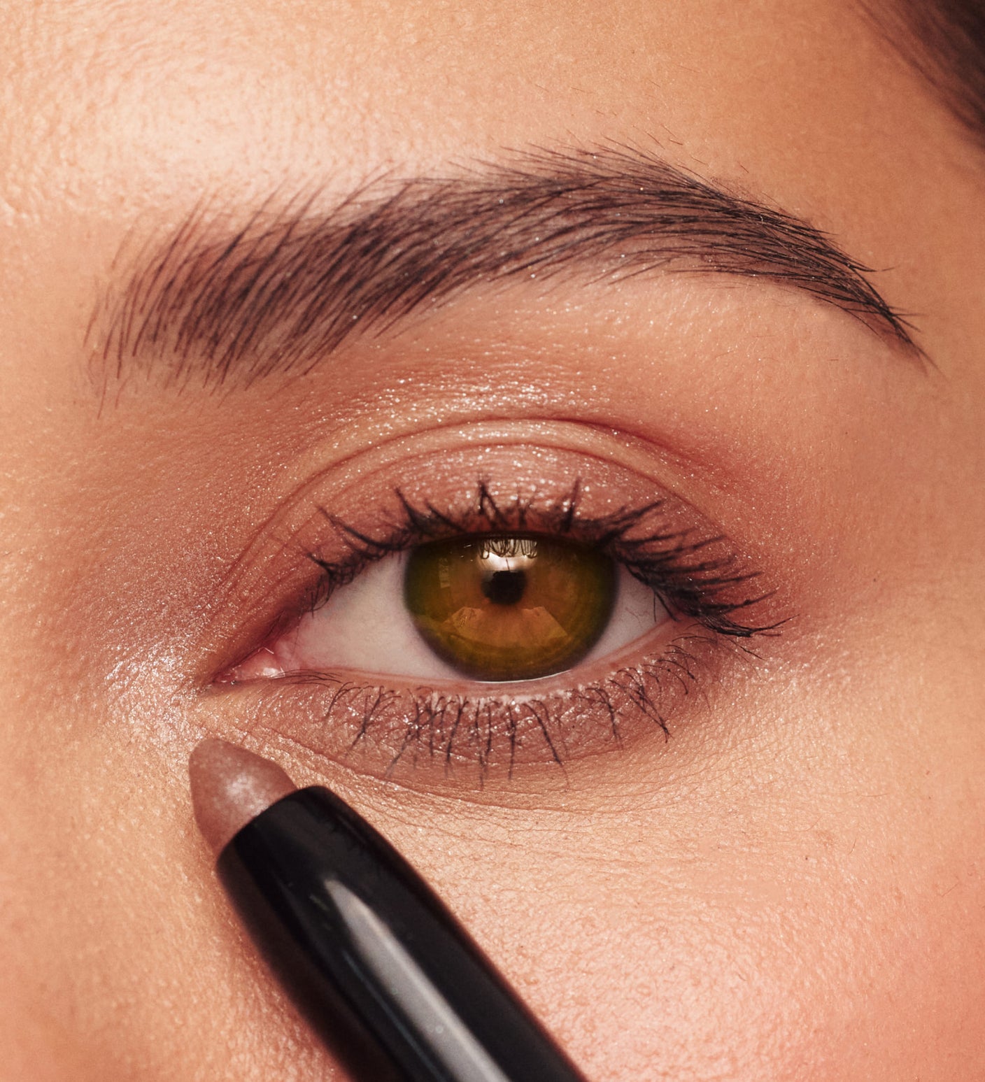 Woman applying Eye Perfecting Shimmer Stick in Bronze from The Summer Set to brighten tired eyes