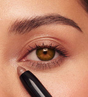 Woman applying Eye Perfecting Shimmer Stick in Bronze from The Summer Set to brighten tired eyes