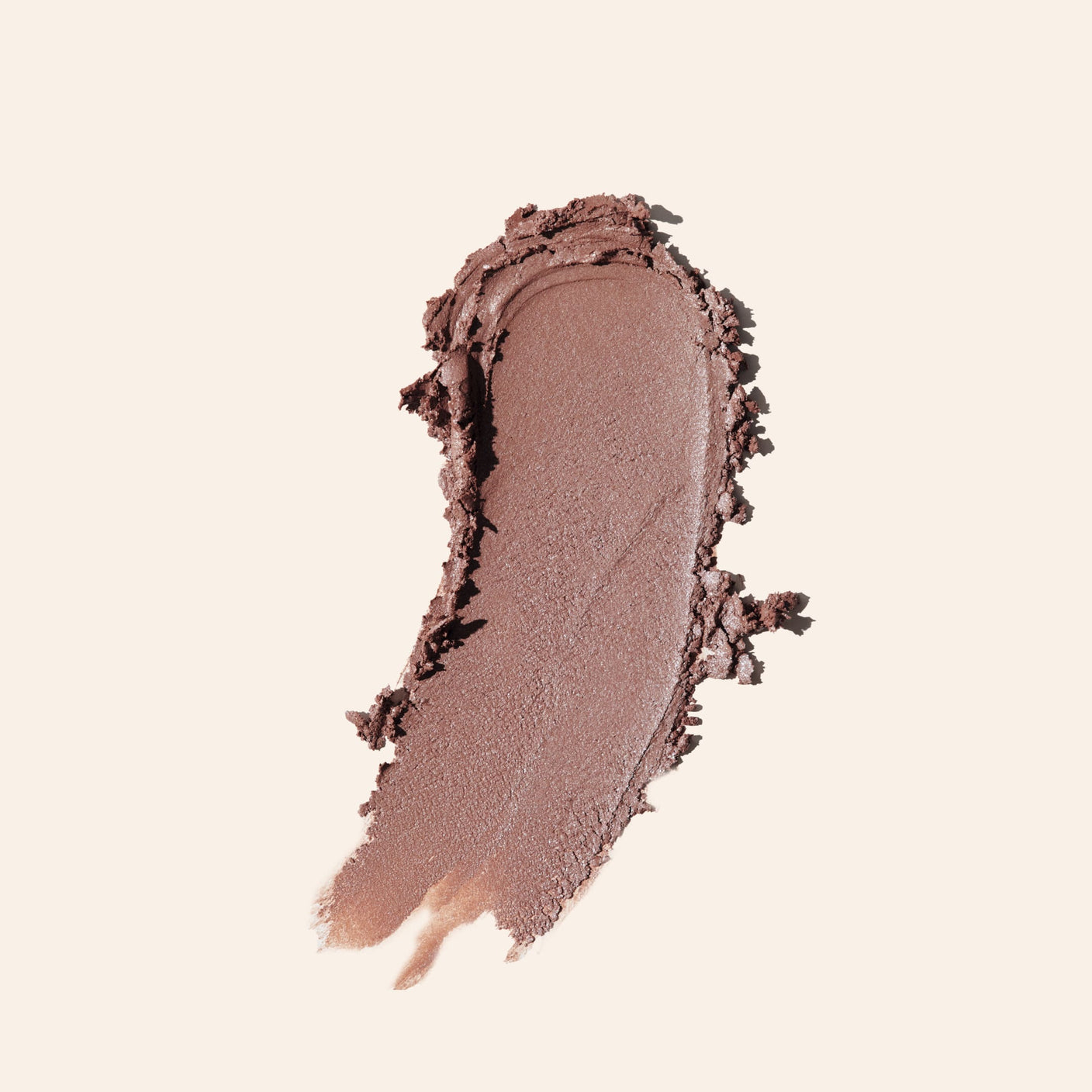 Close-up of a swatch of brown makeup powder on a beige background