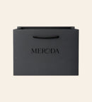 Gift Bag in matte black featuring a woven rope handle and embossed Meroda logo on a cream background.