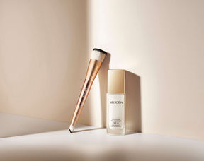 Meroda Cosmetics 2-in-1 Build & Conceal Brush leaning against the Changing Foundation bottle