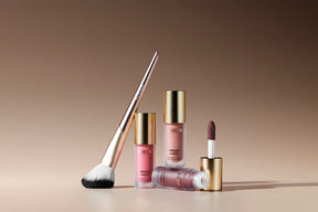Vibrant Cheeks Blush Brush with synthetic bristles and gold handle alongside three Vibrant Cheeks Liquid Blush bottles.