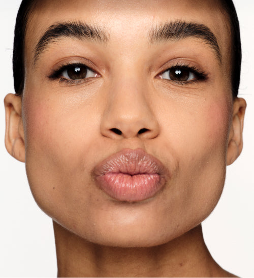 Hydrating Lip Tint in Honey Beige on a model, providing a sheer satin finish and naturally fuller lips.