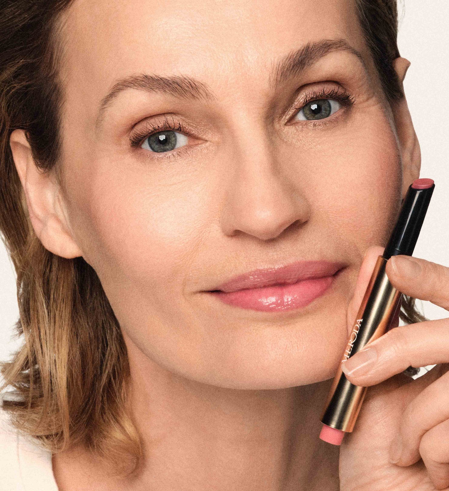 Hydrating Lip Tint in Dusty Rose held by a model for a natural, healthy glow.