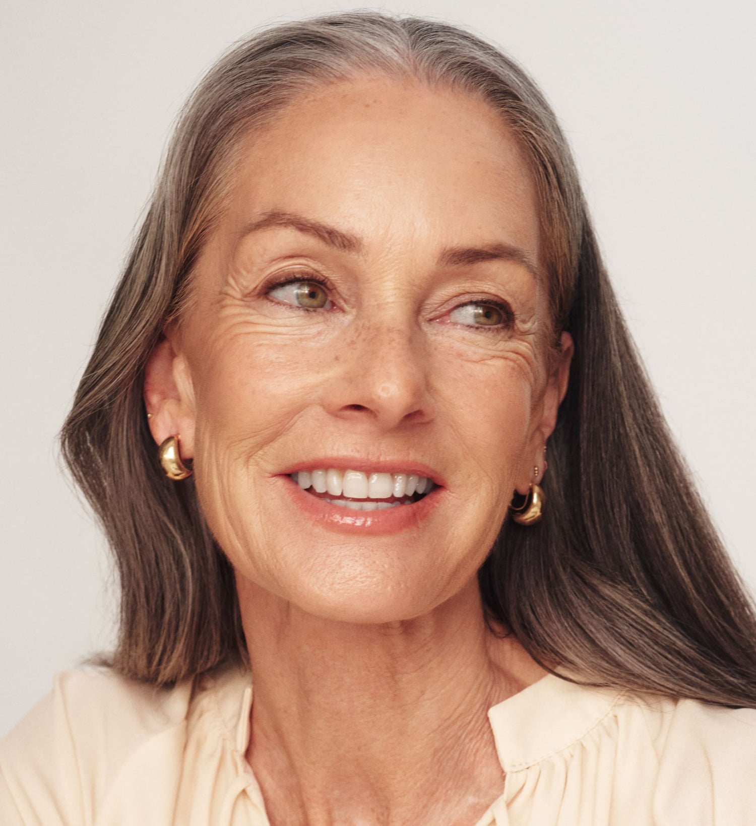 Woman with gray hair smiling against a plain background