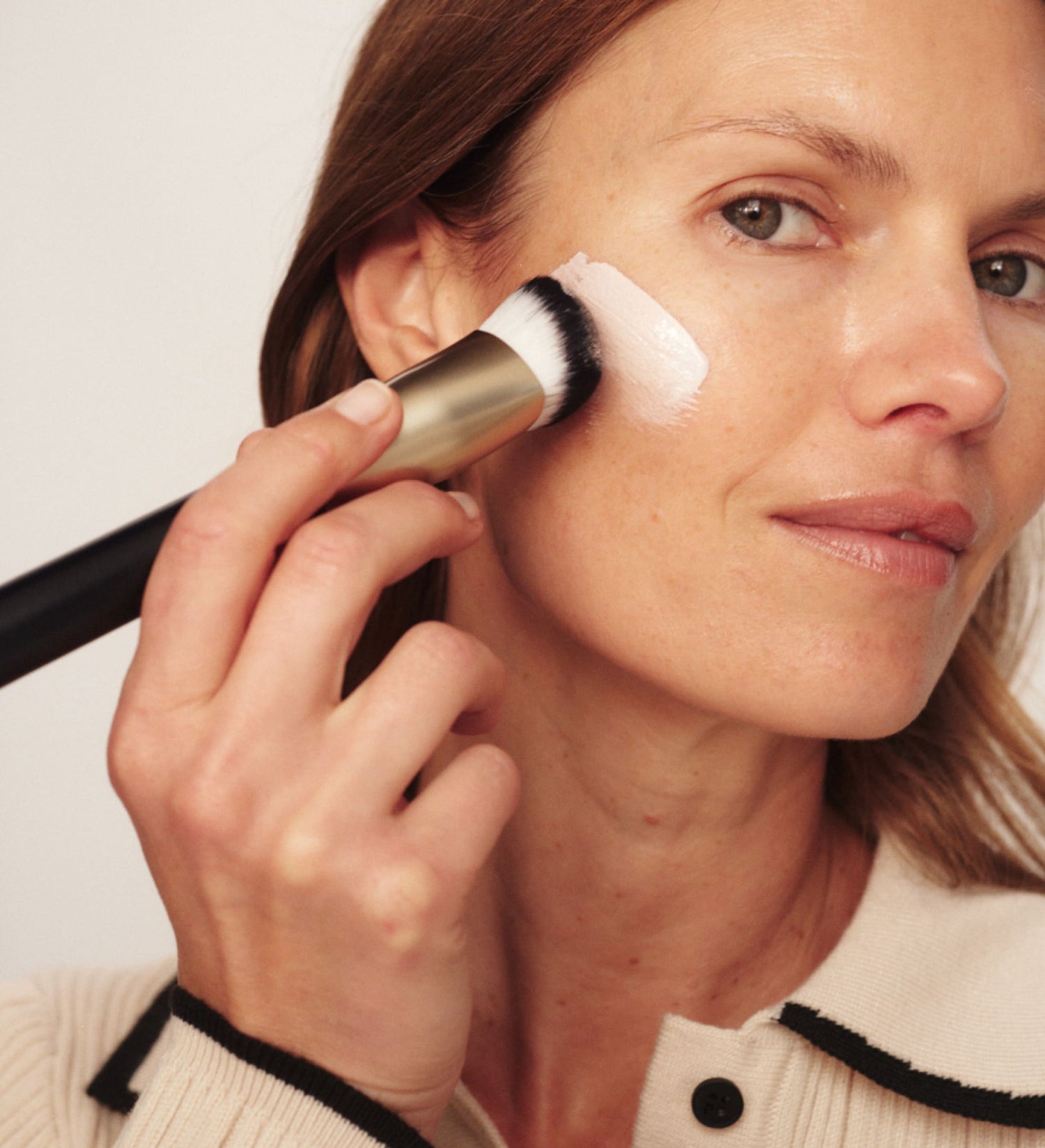 Model applying Changing Foundation with a brush for a seamless, radiant finish.