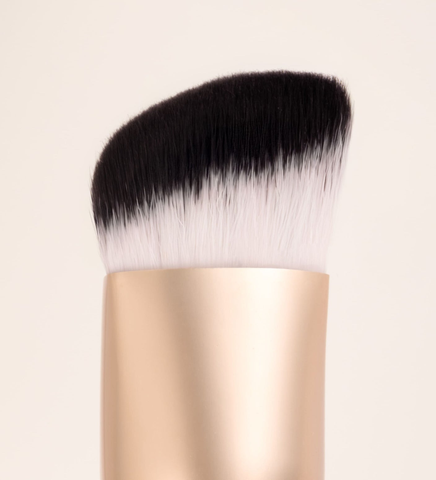 The Essential Brush close-up showing the unique triangular shape and dense synthetic bristles